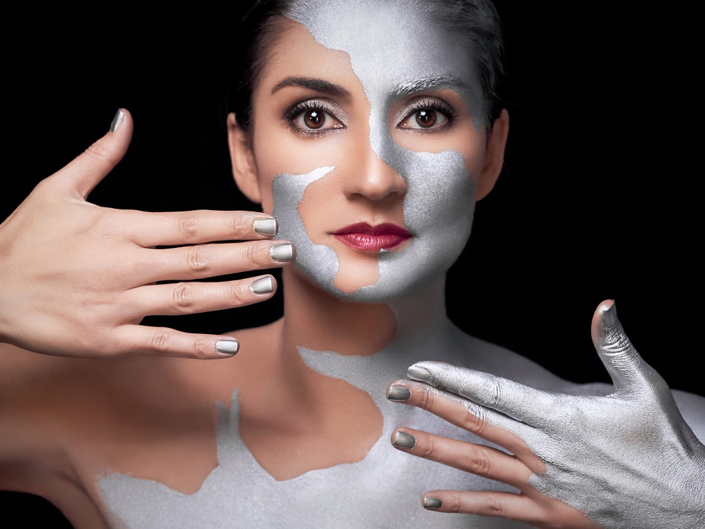 Красивая кареглазая женщина с серебристой краской на теле 