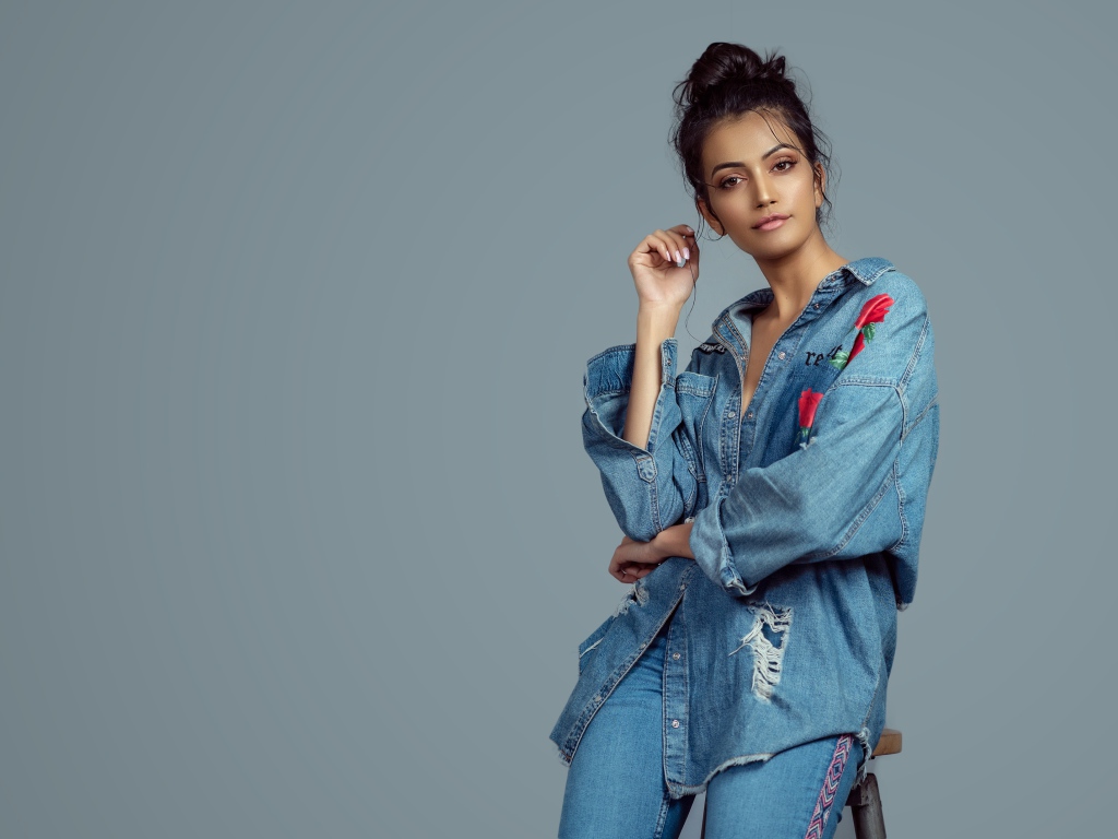 Красивая девушка в джинсовом костюме на сером фоне