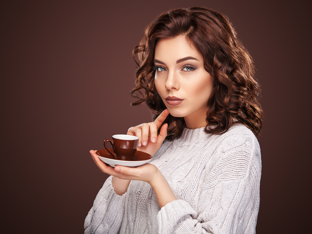 Красивая девушка в белом свитере с чашкой кофе