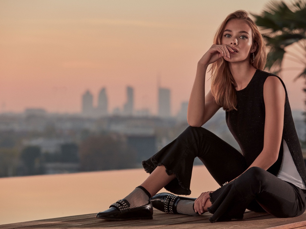 Красивая девушка в черном сидит  на мосту 