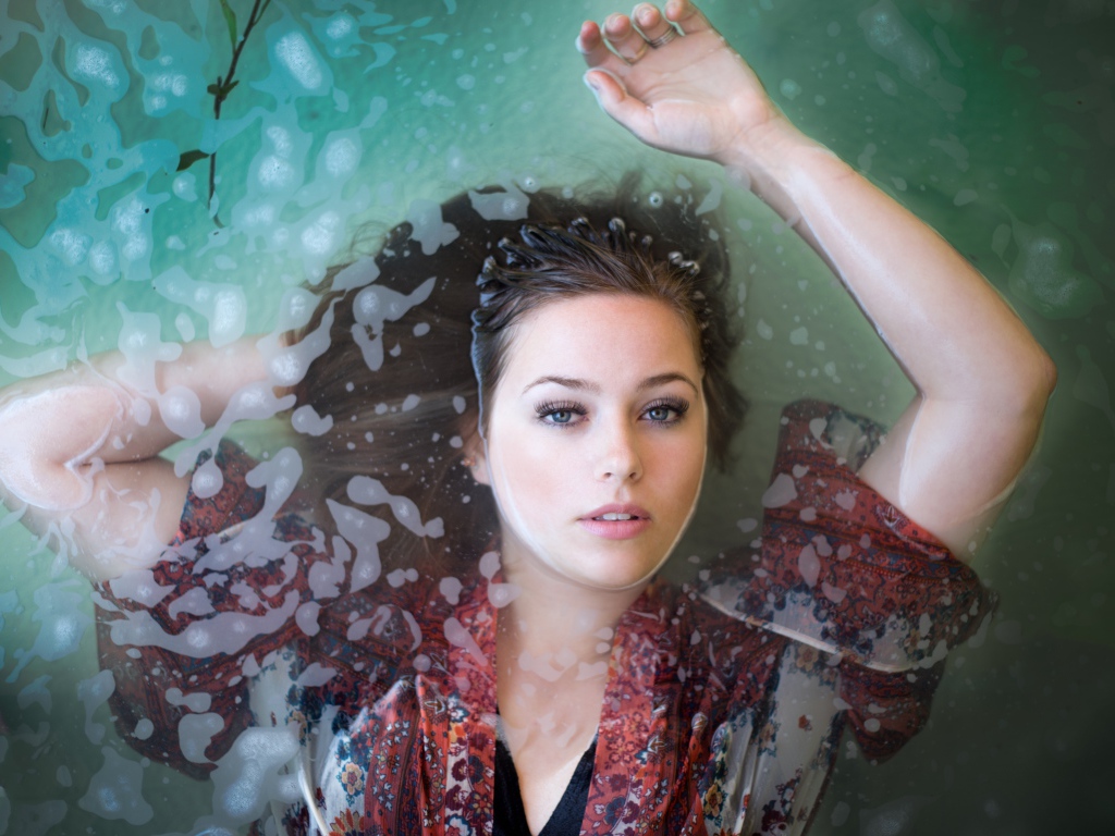 Красивая девушка лежит в одежде в воде 