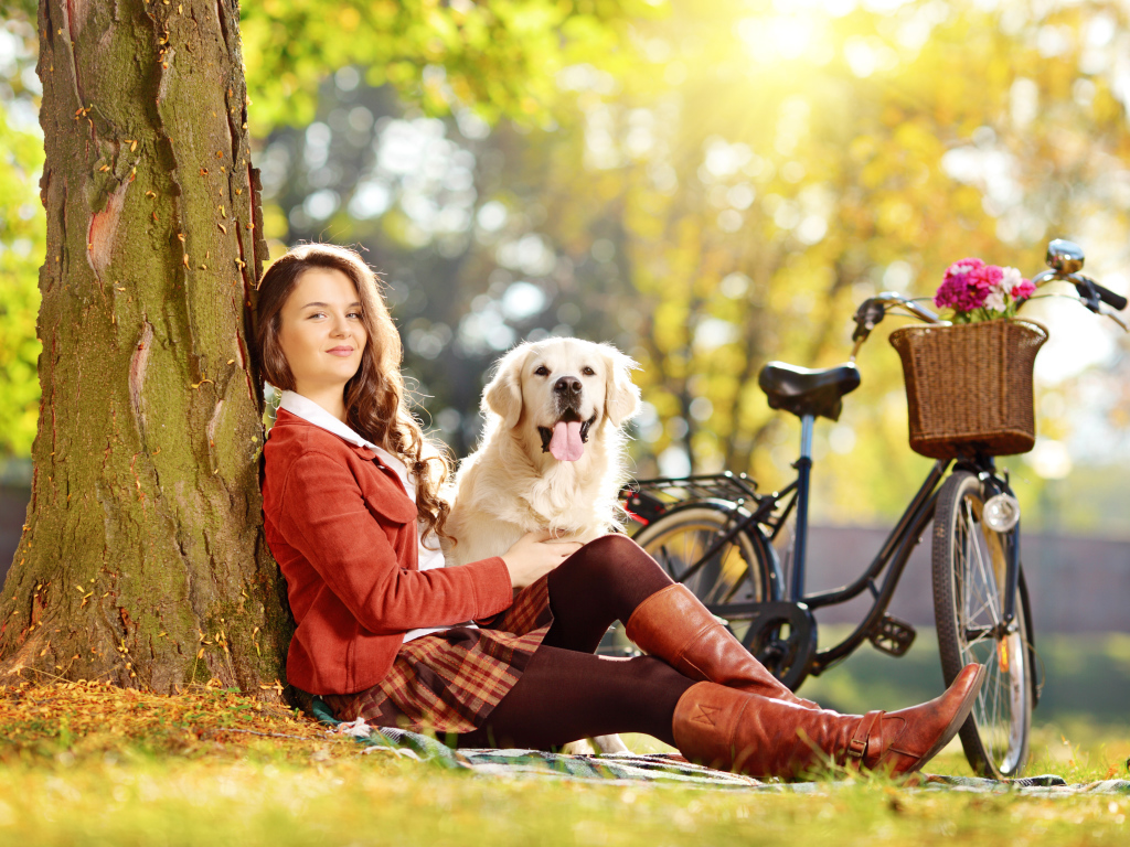 Красивая девушка сидит с собакой у дерева 