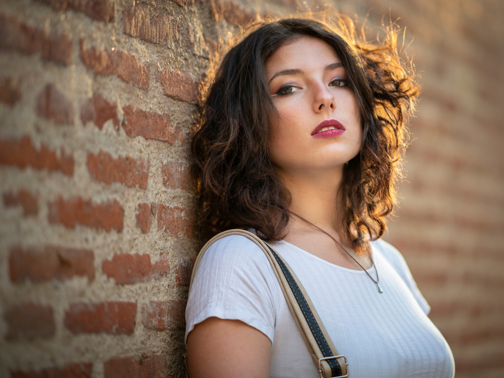 Красивая девушка стоит у стены 