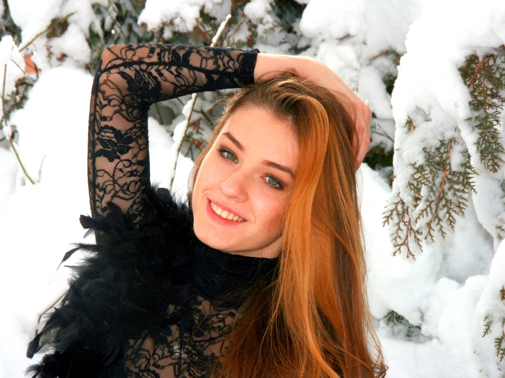 Красивая рыжеволосая девушка у заснеженной туи