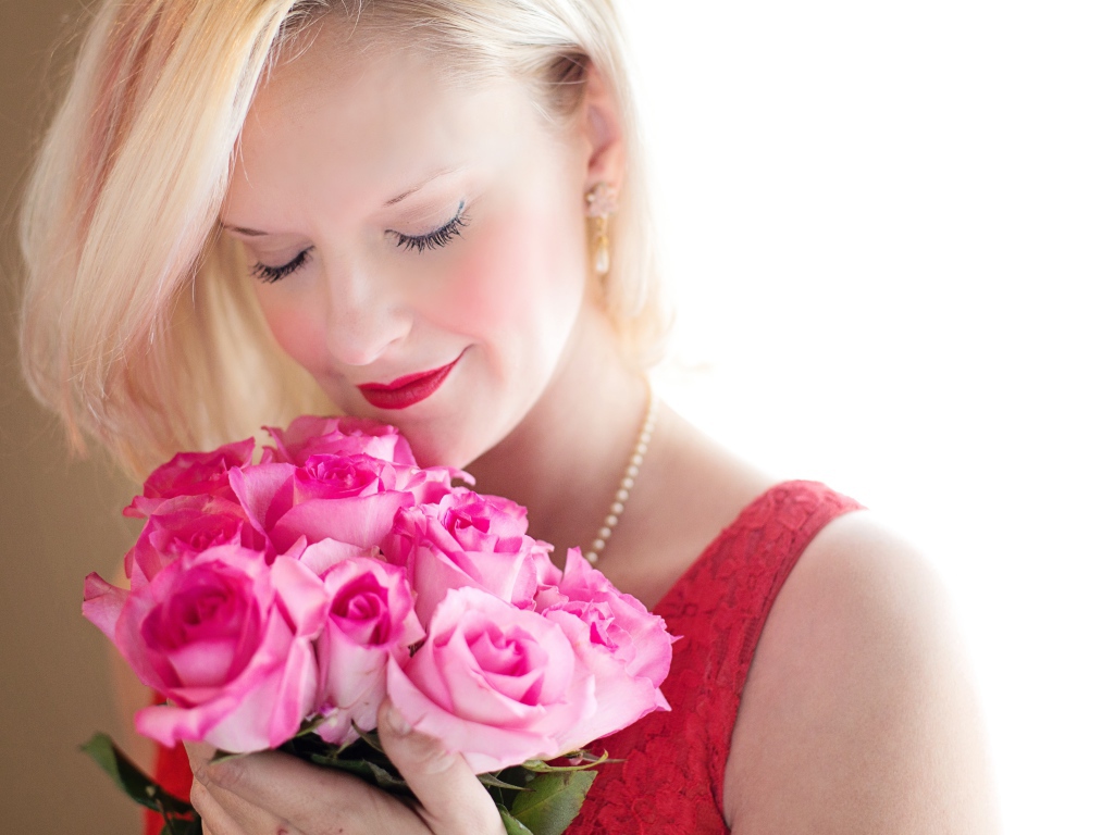 Блондинка с закрытыми глазами нюхает букет роз