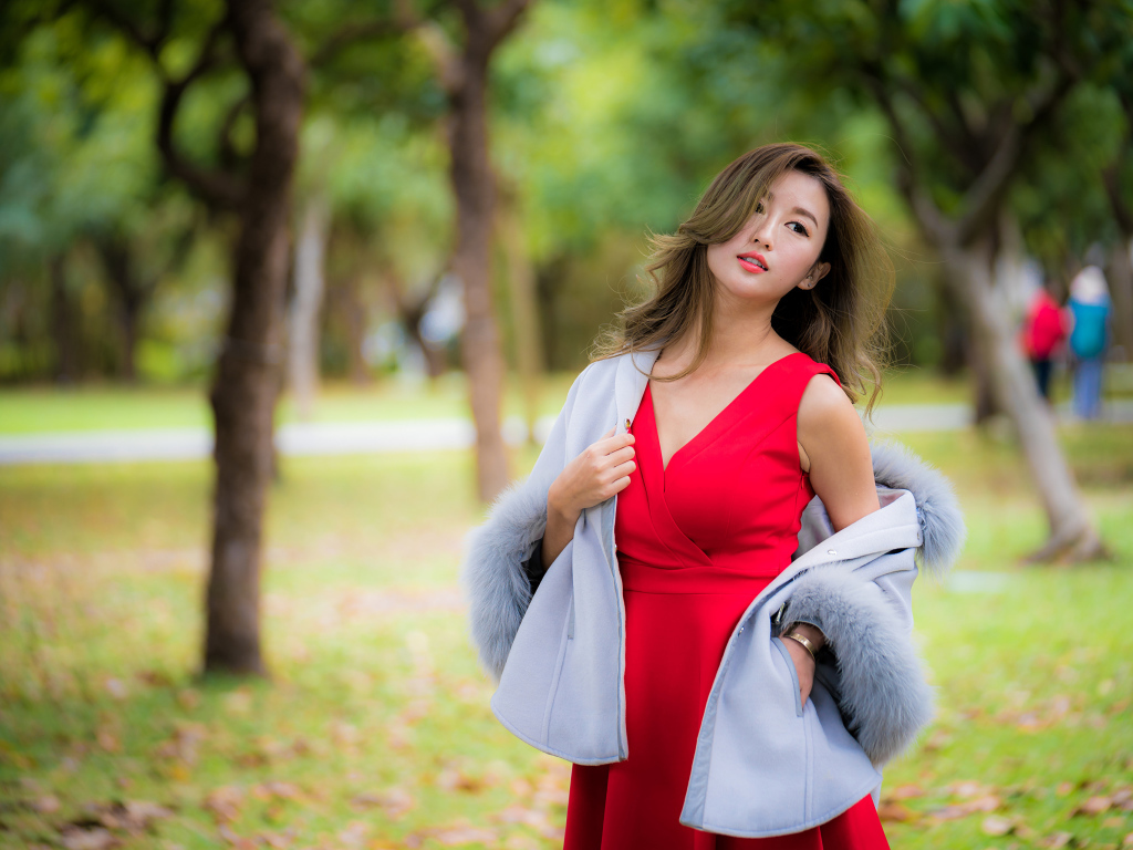 Яркая девушка азиатка в красном платье в парке