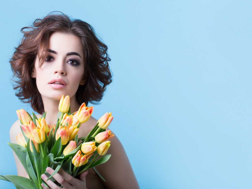 Кареглазая шатенка с букетом тюльпанов на голубом фоне