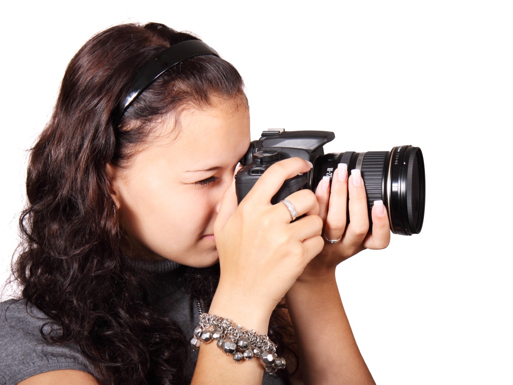 Молодая девушка шатенка с фотоаппаратом в руках на белом фоне