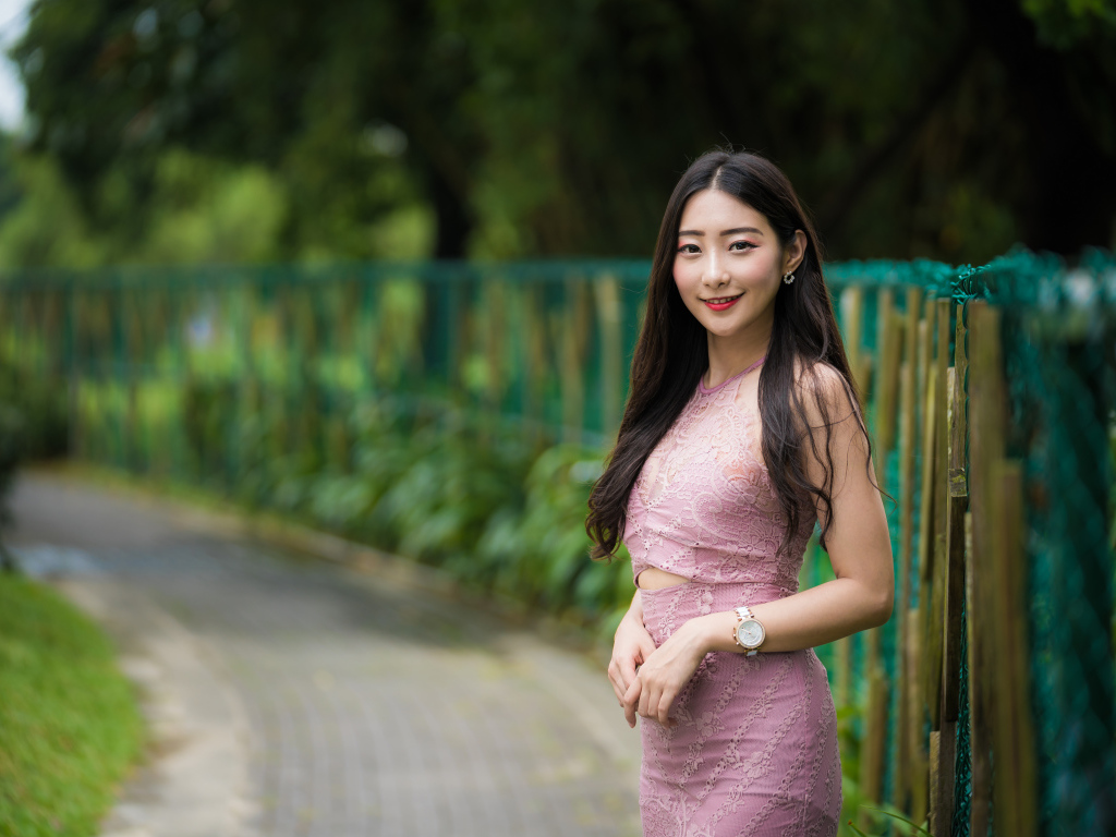 Милая улыбающаяся азиатка в костюме у забора