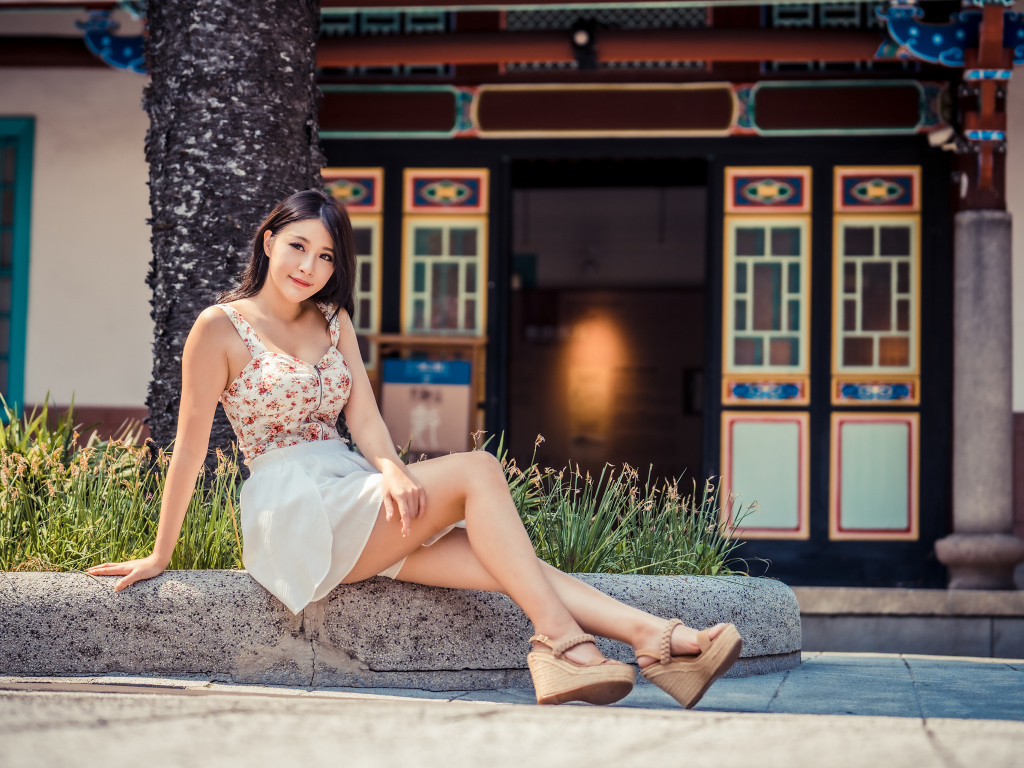 Милая улыбающаяся девушка сидит на бордюре