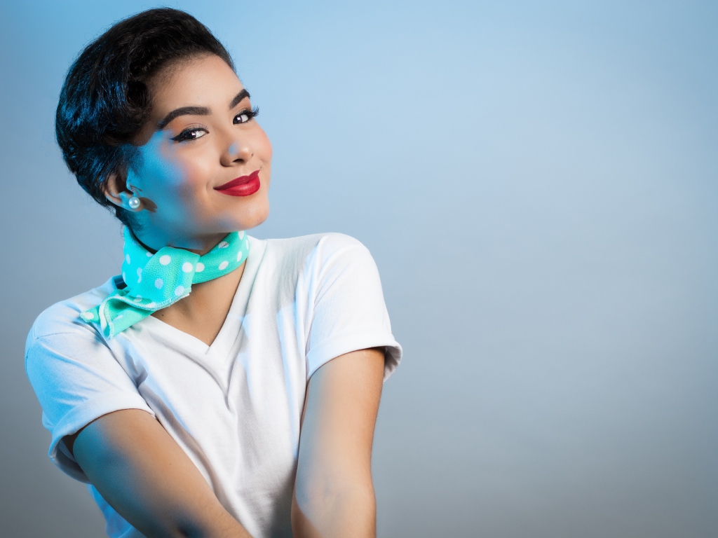 Милая улыбающаяся девушка с шарфом на шее на сером фоне