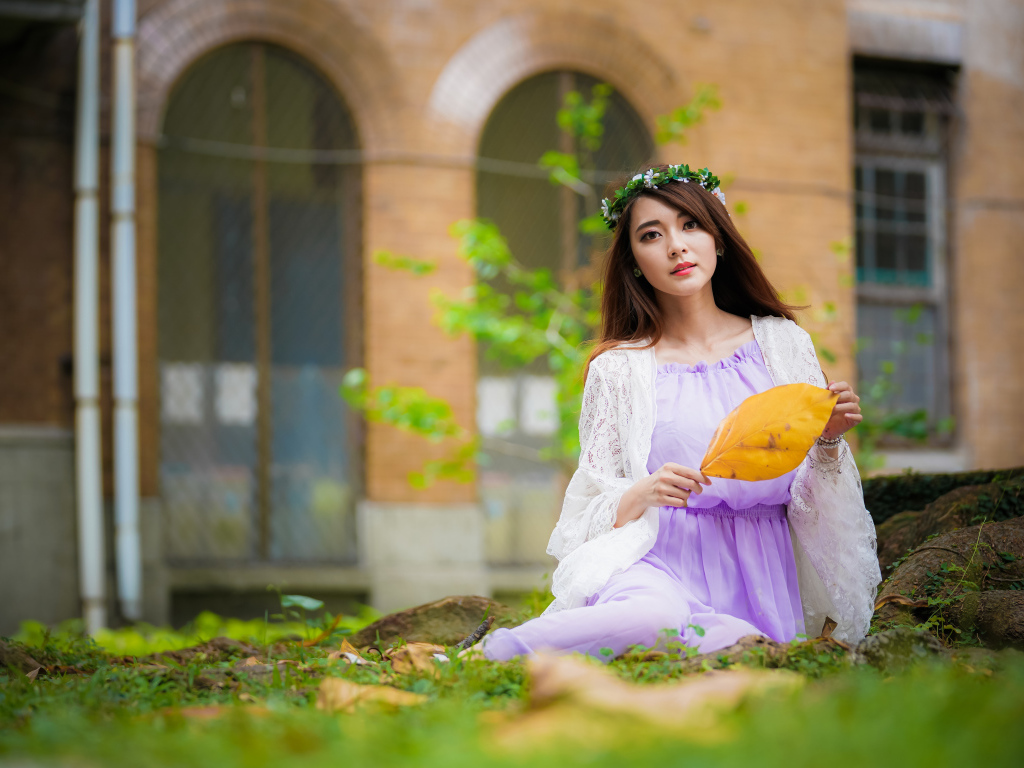 Девушка в красивом платье сидит на траве 