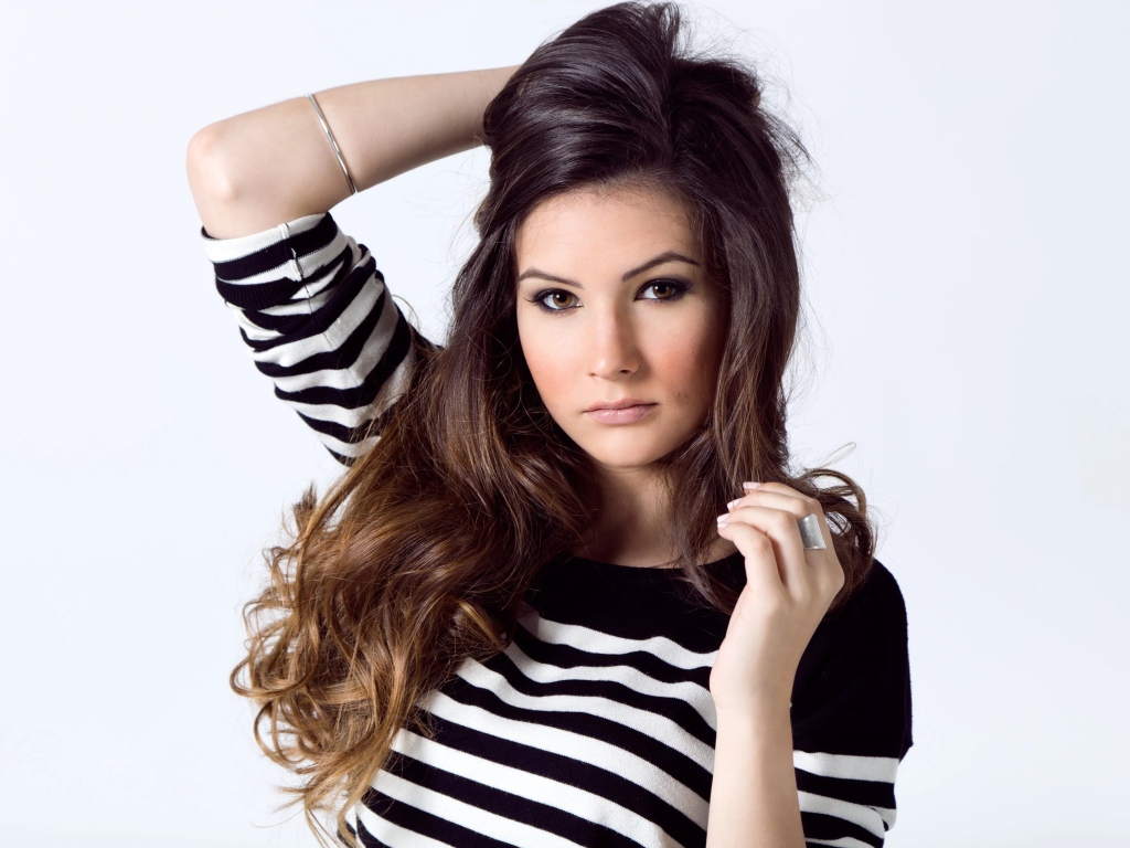 Девушка в полосатом свитере с рукой в волосах на белом фоне