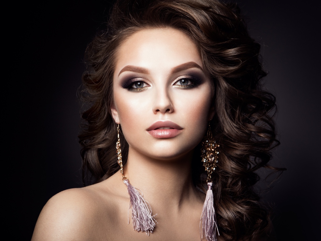 Девушка с прической с красивыми сережками на сером фоне 