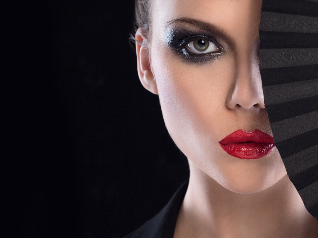 Девушка с макияжем закрывает лицо веером