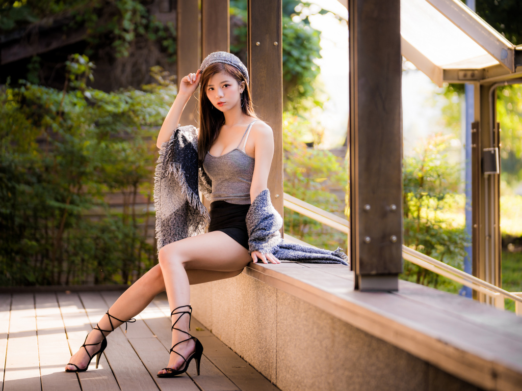 Длинноногая азиатка сидит на окне 