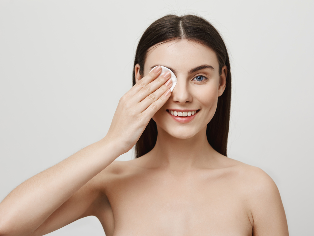 Настоящая голубоглазая девушка снимает макияж с лица