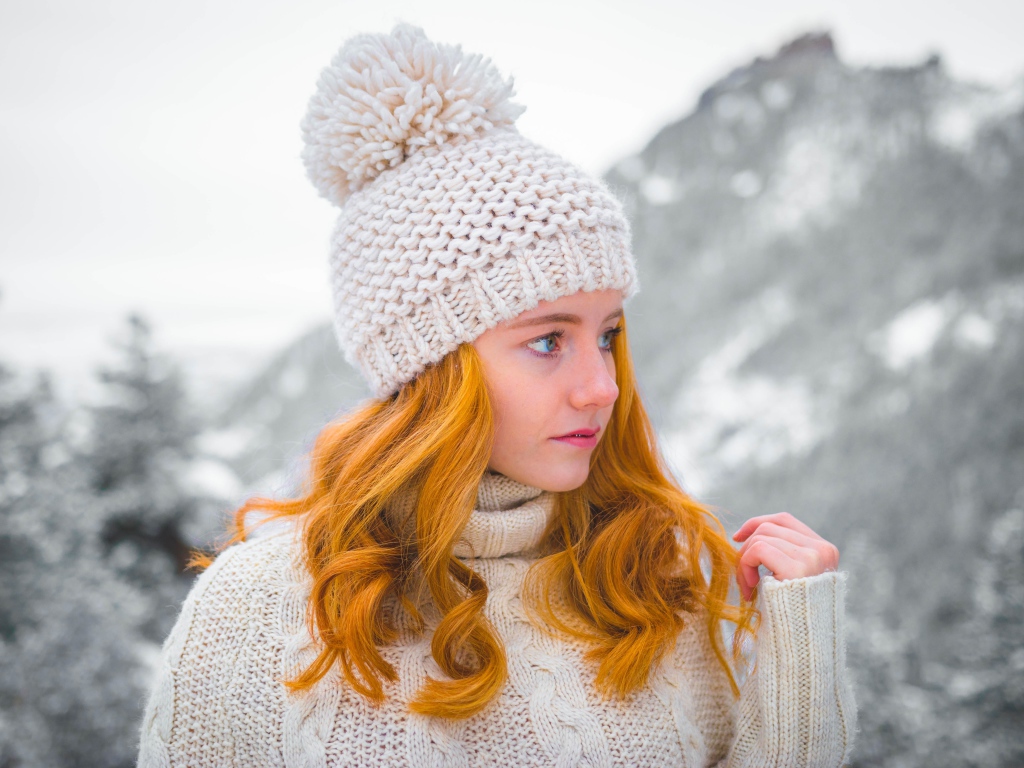 Рыжеволосая девушка в теплой шапке зимой 