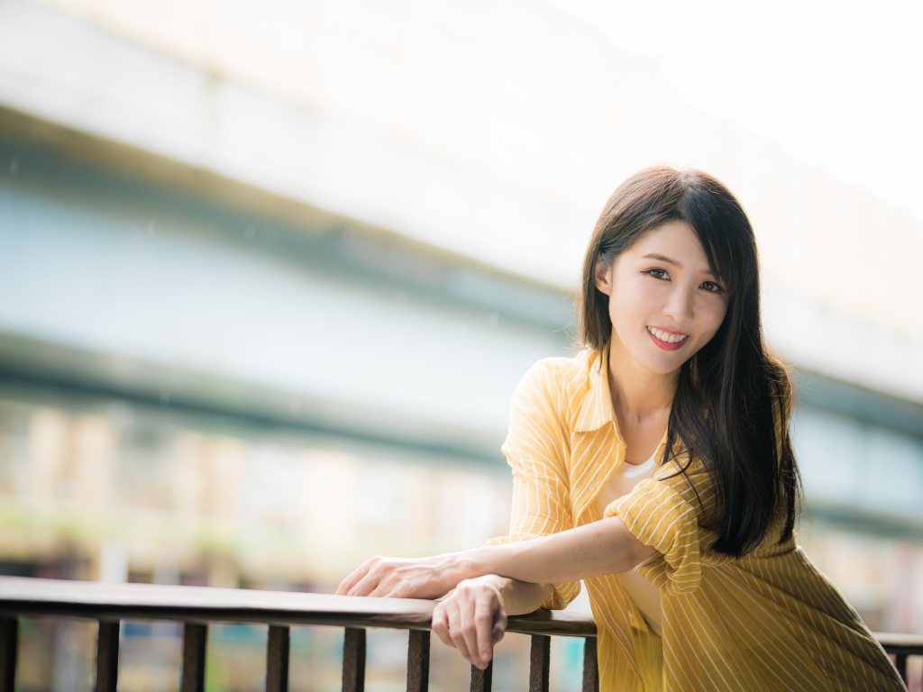 Улыбающаяся азиатка в желтой полосатой рубашке