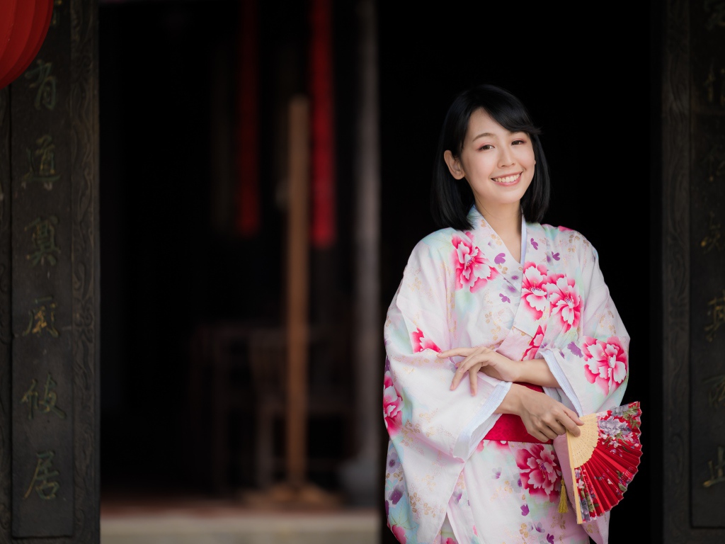 Улыбающаяся девушка азиатка в кимоно с веером в руке