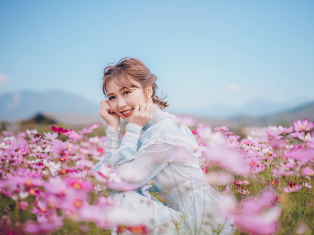 Улыбающаяся девушка азиатка на поле с цветами космеи 