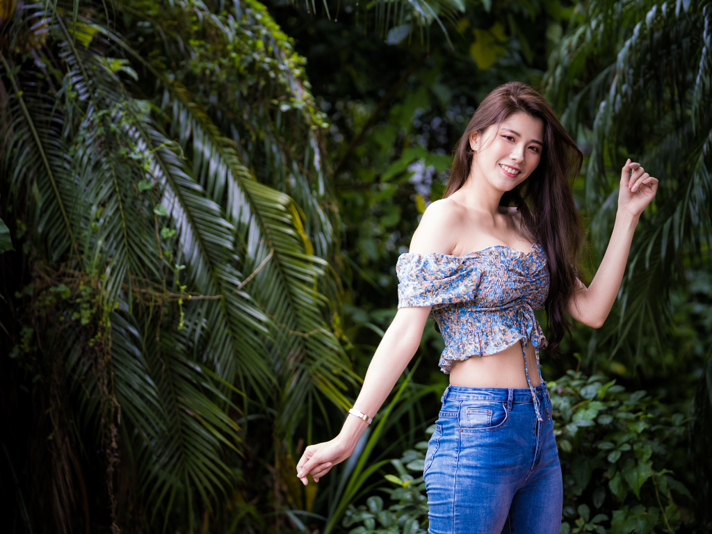 Улыбающаяся азиатка на фоне зеленых листьев