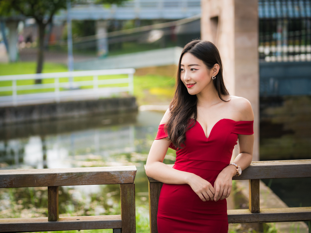 Улыбающаяся девушка в красном платье у перил 