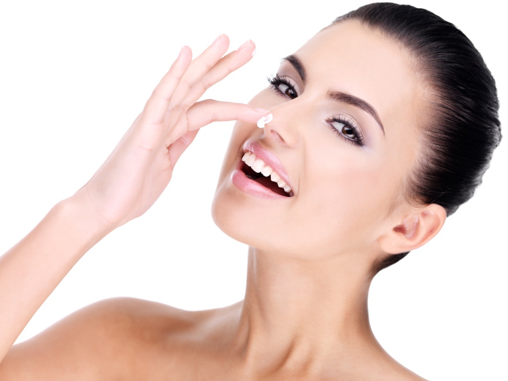 Улыбающаяся девушка мажет крем на нос 