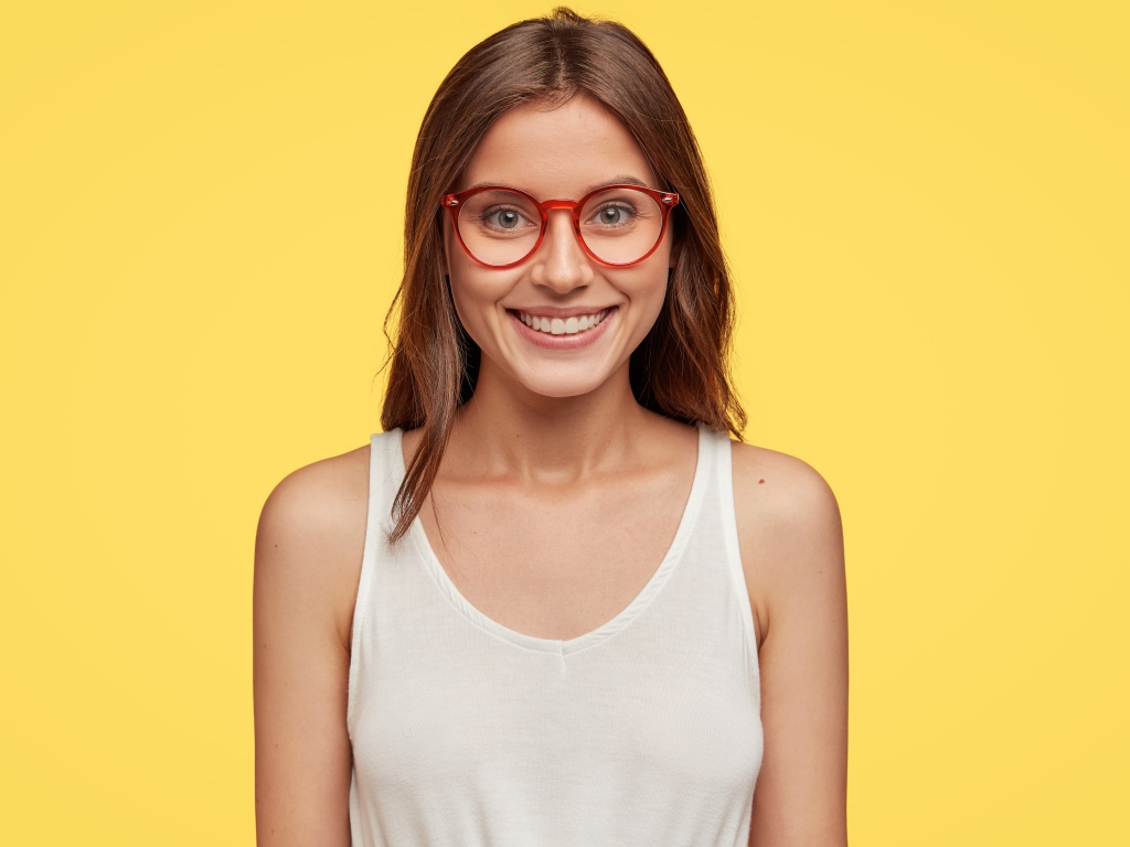 Улыбающаяся девушка в очках на желтом фоне 