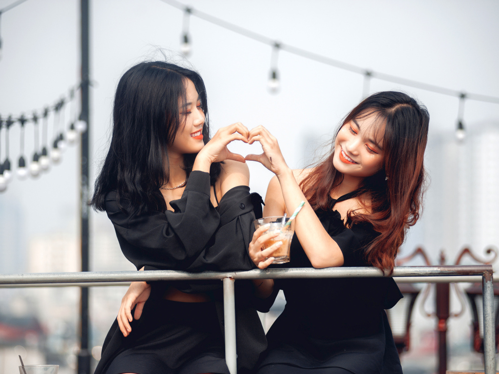 Две девушки азиатки делают сердце руками 