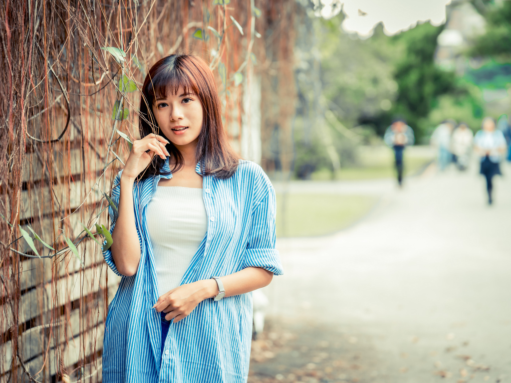 Молодая азиатка в рубашке у стены