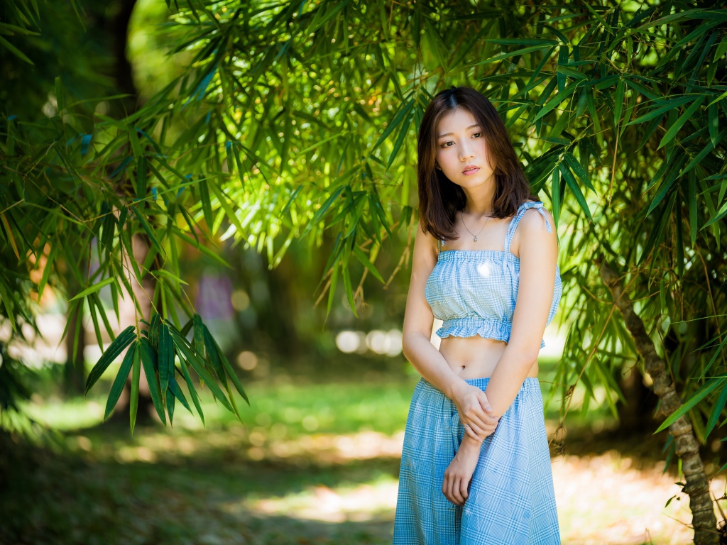 Молодая девушка в голубом костюме под деревом