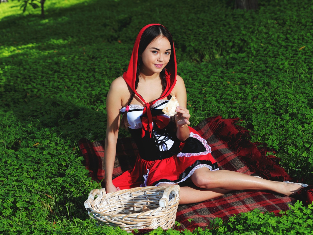 Молодая девушка в костюме сидит на траве, косплей