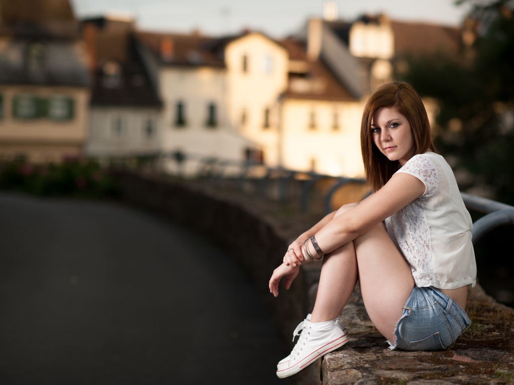 Молодая девушка с короткими  волосами сидит на улице