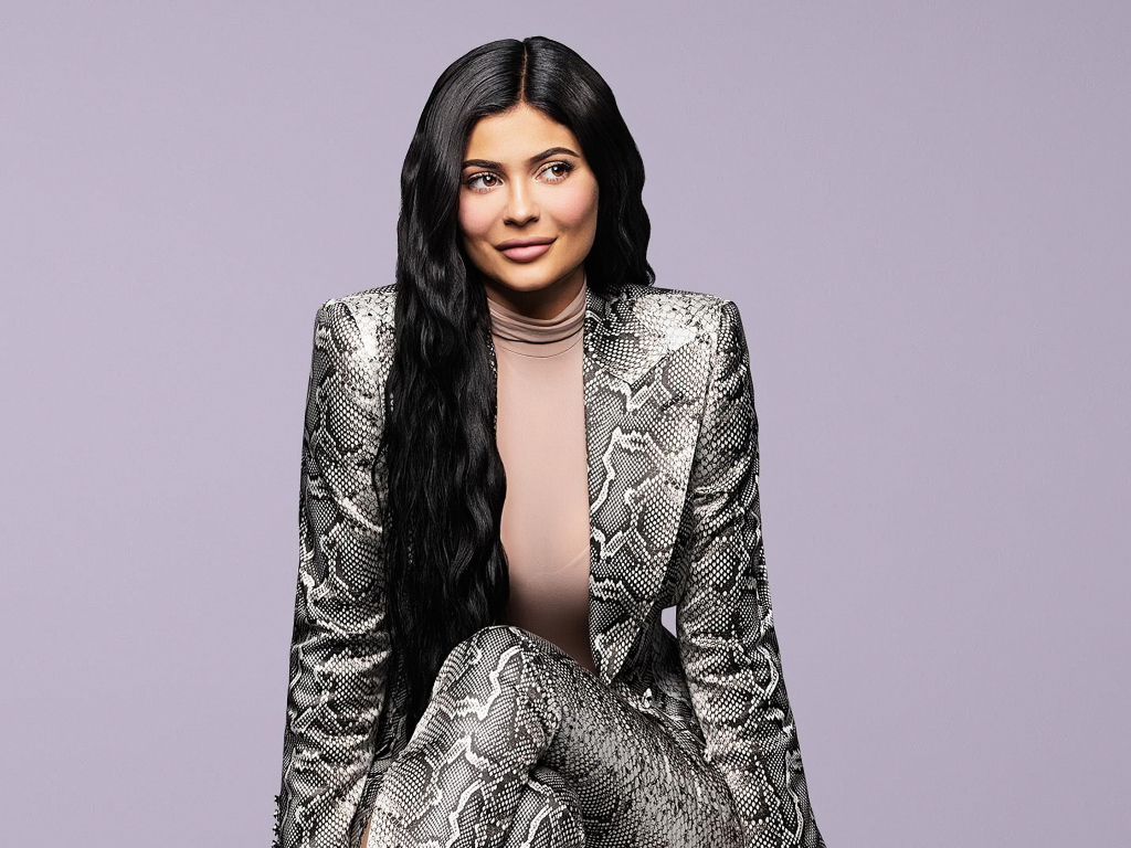 Длинноволосая модель Кайли Дженнер в костюме на сером фоне