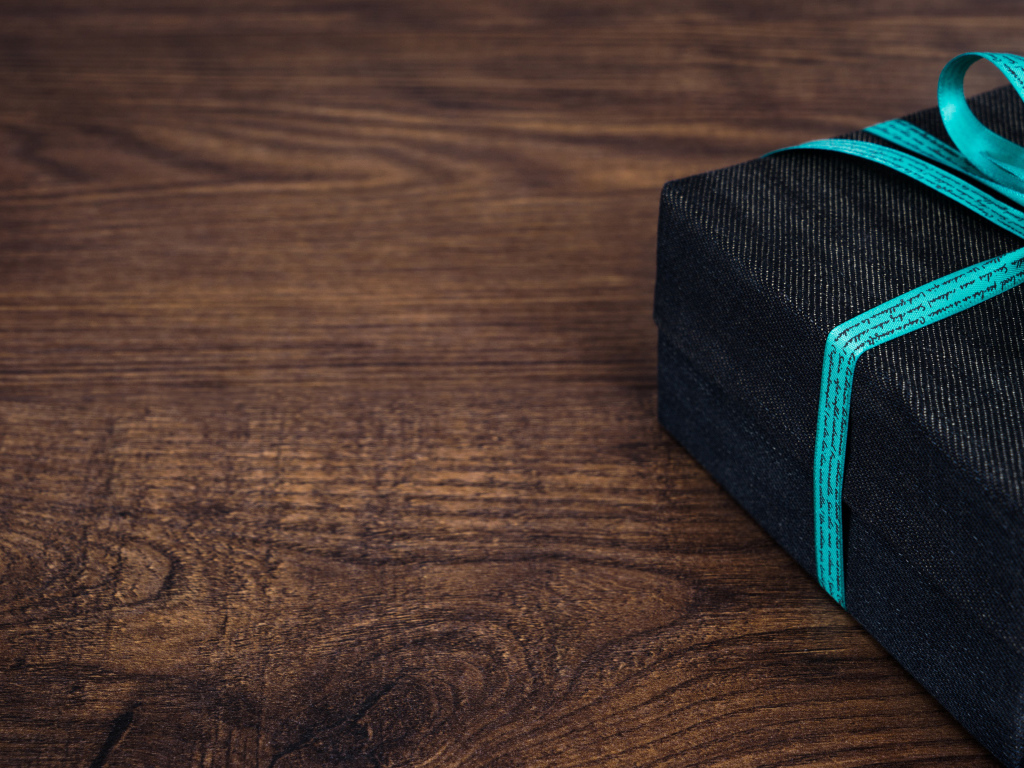 Подарок с синим бантом на деревянном столе 