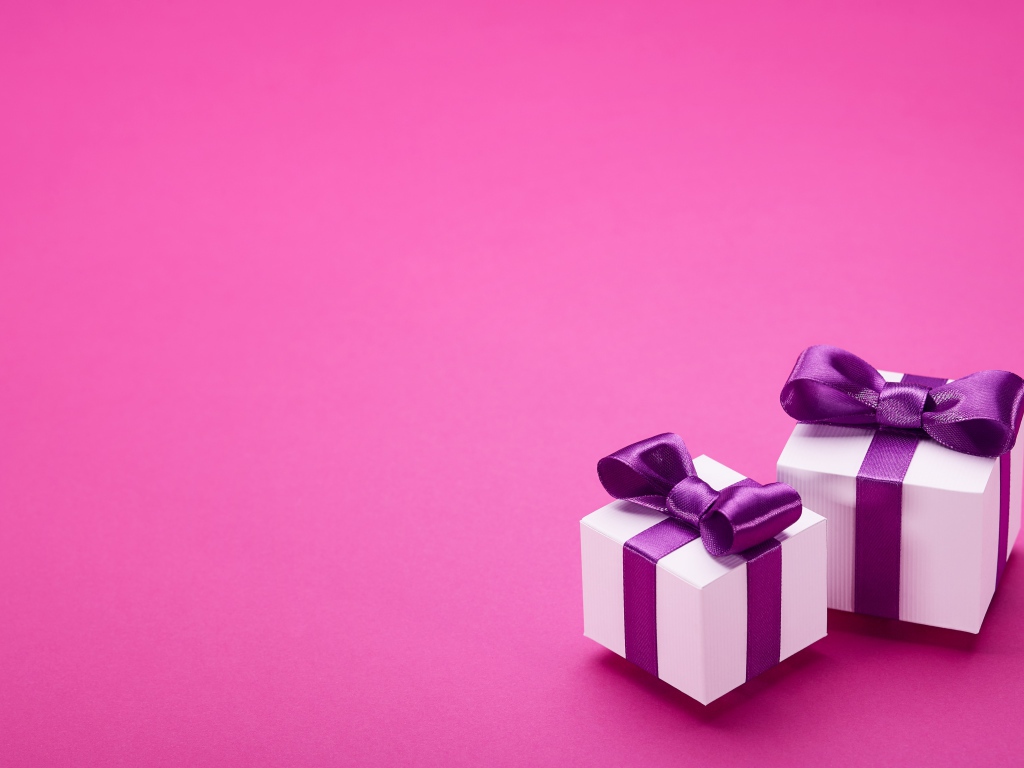Два подарка с бантами на розовом фоне 