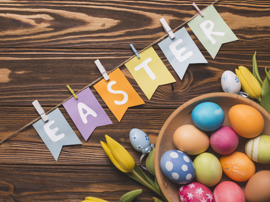 Надпись Пасха на столе с крашеными яйцами и тюльпанами