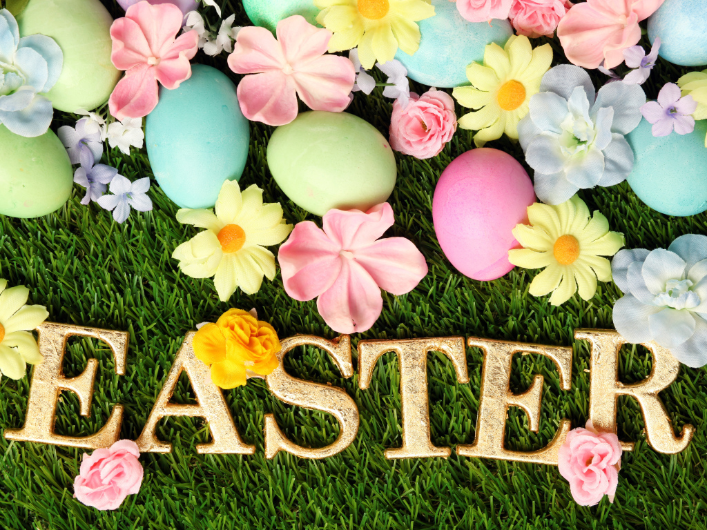 Надпись на траве с разноцветными яйцами и цветами на Пасху
