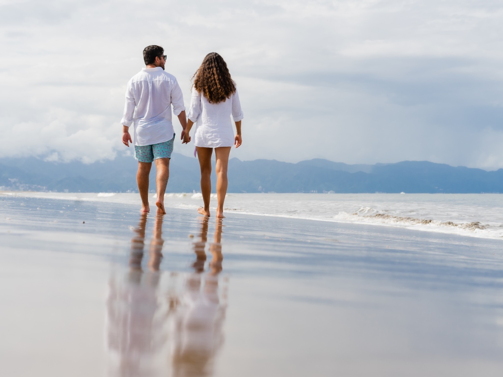 A couple in love walks on the wet sand by the sea