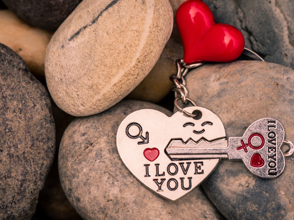 Брелок в форме сердца с ключом лежит на камнях 