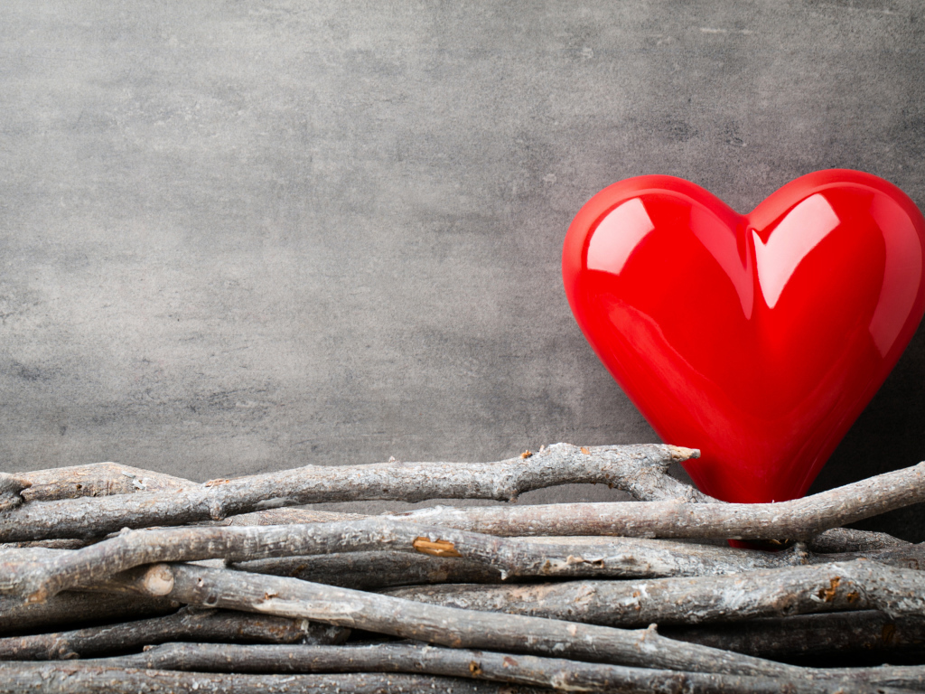Большое красное сердце на сером фоне с деревянными прутьями