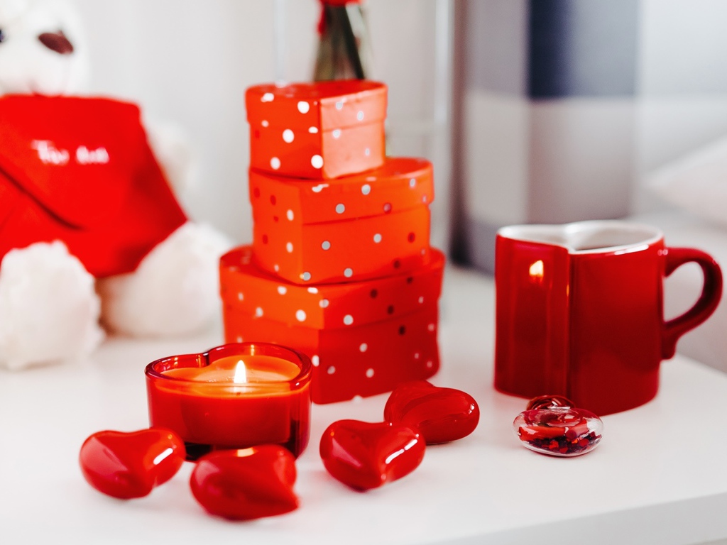 Чашка кофе на столе с подарками, зажженными свечами и сердечками