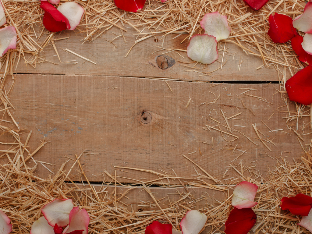 Сено и лепестки роз на деревянном столе 