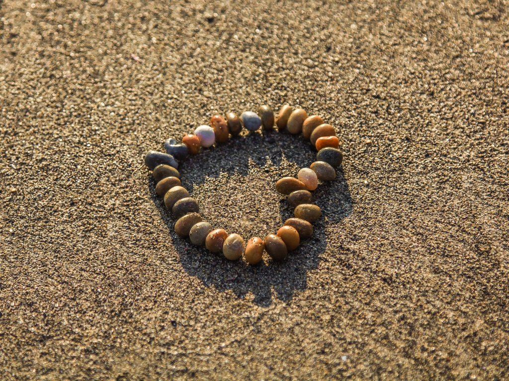 Сердце из мелкий морских камей на песке 