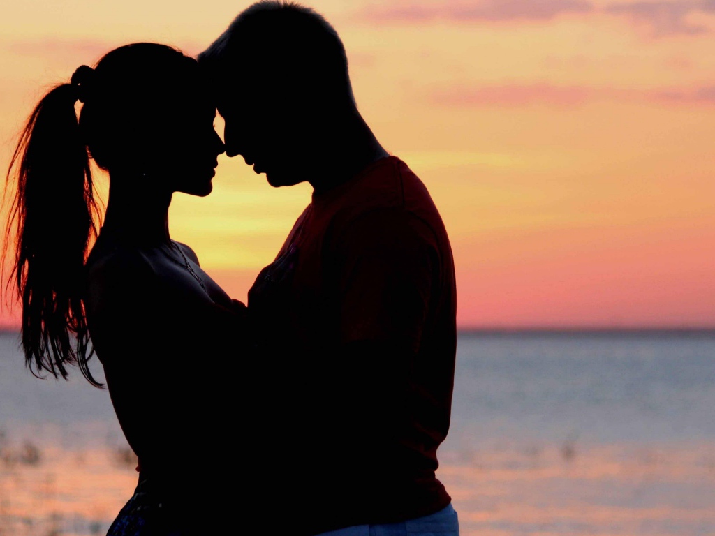 Влюбленная пара на фоне моря в сумерках 