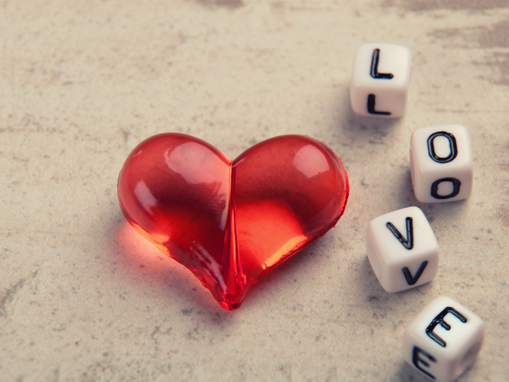 Красное стеклянное сердце на столе с кубиками