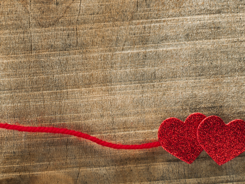 Два красных сердца со шнурком на деревянном фоне