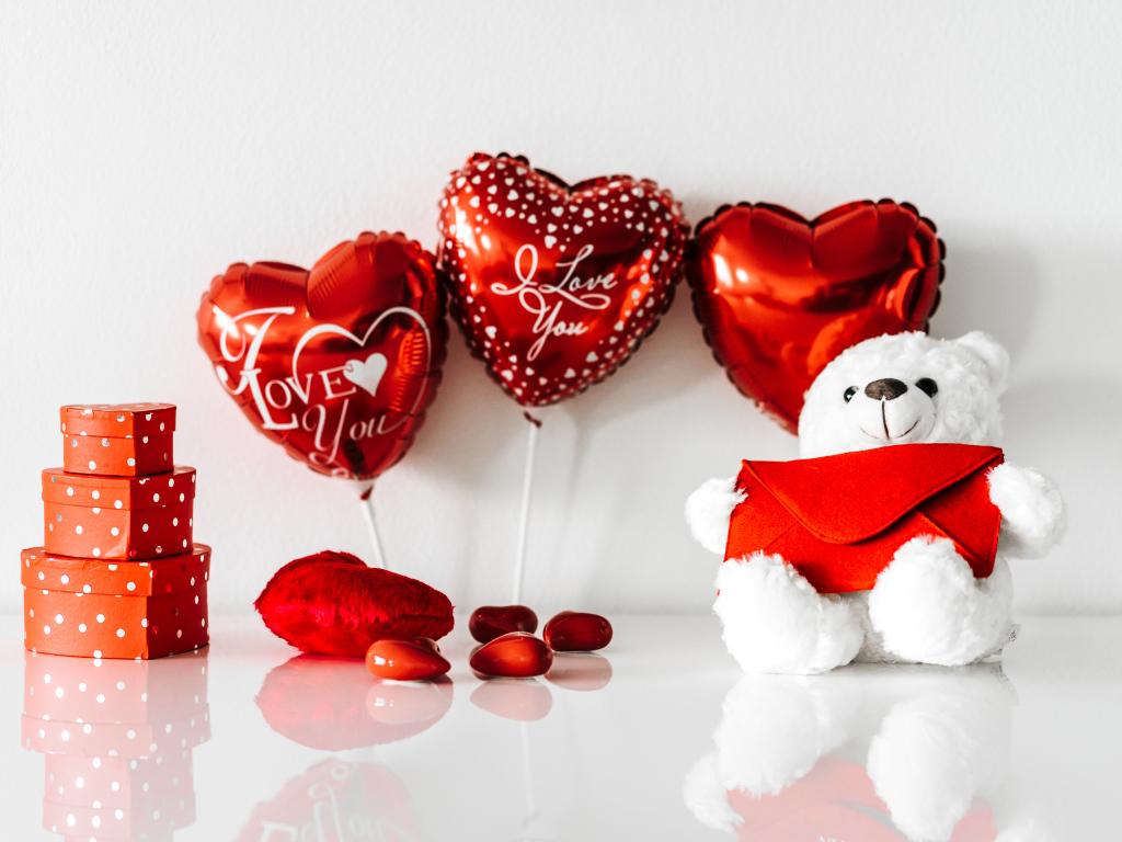 Белый мишка с подарками и шариками у стены