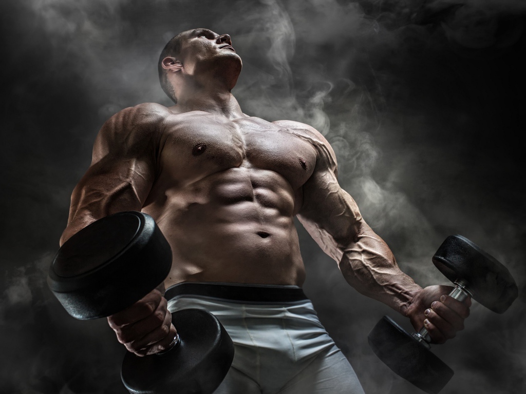 Мужчина бодибилдер с тяжелыми гантелями в руках